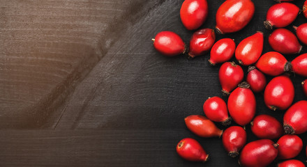 Rosehip on the black wooden table. Ingredient for medicinal tea, top view and copy space