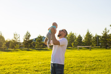 Happy father holding baby son, throwing baby in air. Concept of happy family, father's day and child.