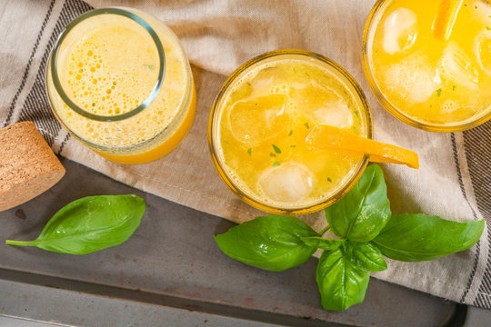 Homemade orange juice with ice cubes and basil leaves in glass