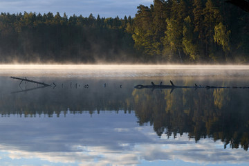 Sunshine over a lake in the background of the forest. Autumn sunrise in Lithuania.
