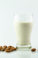 Almond milk in glass with almonds seed on white background
