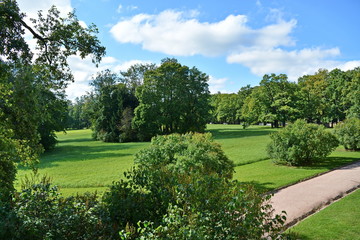 Path to the hill in a beautiful city Park past the trees and smoothly trimmed lawn with green grass on a Sunny summer day on background of blue sky with white cloud. Top view