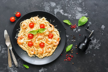 Spaghetti with shrimps and cherry tomatoes on a black rustic background. Top view,flat lay.