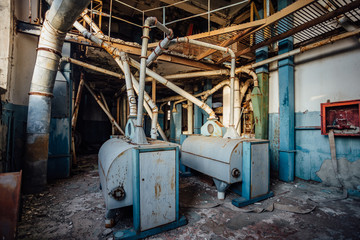 Fototapeta na wymiar Abandoned flour milling factory. Old rusty roller mill equipment with pipeline