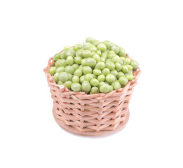 Green fresh peas in a wicker basket on a white isolated background