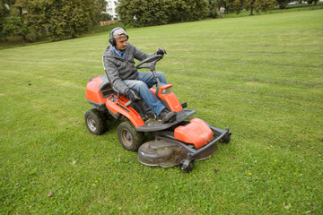 Fototapeta premium lawn mower tractor working in the town park