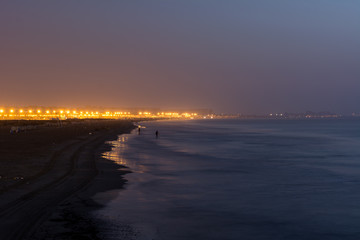 Obraz premium Long exposure landscape low light photo of beach in Valencia in Spain in early morning with city lights in background