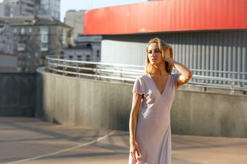 Glamorous tanned model in trendy outfit posing at the background of metal shutters. Space for text