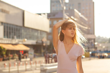 Fototapeta premium Pretty blonde model posing at the street in a rays of sun. Lifestyle fashion concept. Space for text
