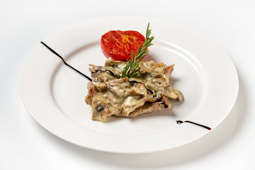 Plate of beef steak served with white mushrooms sauce and tomato isolated at white background.