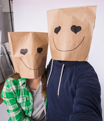Valentine's day concept - Young love couple with bags over heads making selfie on smartphone