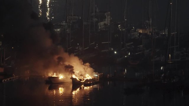 During the night, firefighters try to put out two luxury yachts that are catching fire at the marina berth