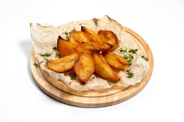 Fried potato wedges on a wooden tray board with paper isolated at white background.
