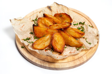 Fried potato wedges on a wooden tray board with paper isolated at white background.