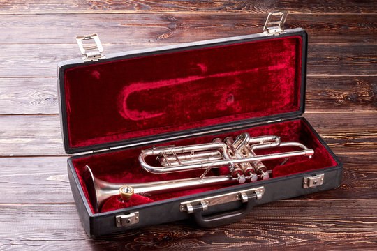 Golden trumpet in velvet case. Brassy trumpet in square box on wooden background. Classical music instrument.