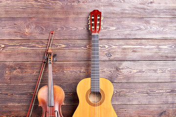 Acoustic guitar and violin on wooden background. Vintage musical instruments on textured wooden surface with text space.