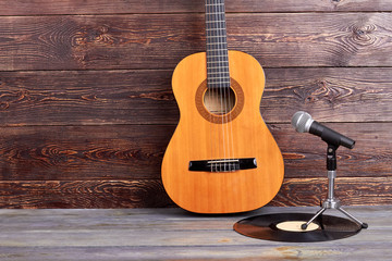 Acoustic guitar, vinyl record and microphone. Musical instruments on wooden background and copy...