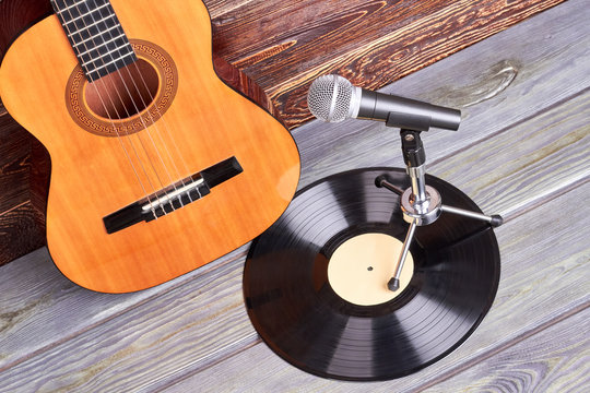 Guitar, vinyl record and microphone. Vintage musical instruments on wooden background.