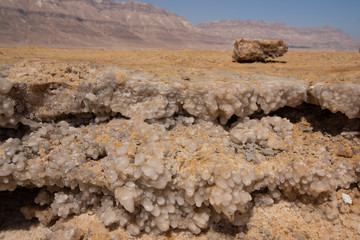 Fototapeta na wymiar Salt forming on the shore of the sea in Israel with the desert behind