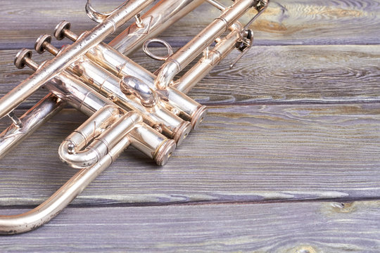 Vintage trumpet and copy space. Old musical instrument on wooden background. Retro jazzy equipment.