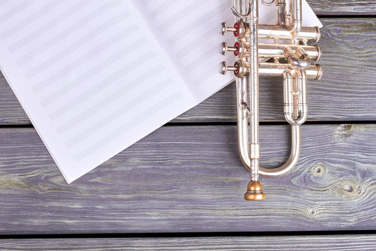 Old musical instrument on wooden background. Vintage trumpet and musical notes, copy space.