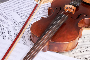Vintage violin on musical notes. Old viola and musical notes sheets. Classical music background.