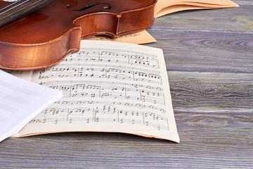 Sheets of musical notes and violin. Vintage musical instrument on old wooden background. Music still life. - obrazy, fototapety, plakaty