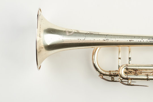 Part of rusty trumpet instrument. Old classical trumpet on light background, cropped image. Antique instrument of orchestra.