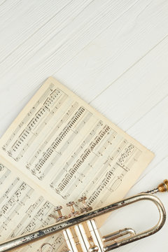 Vintage trumpet and music notes, top view. Old trumpet, musical notes and copy space. Classical orchestral instrument.