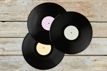 Three vinyl records with different labels. Set of vinyl discs on wooden boards, top view. Retro...