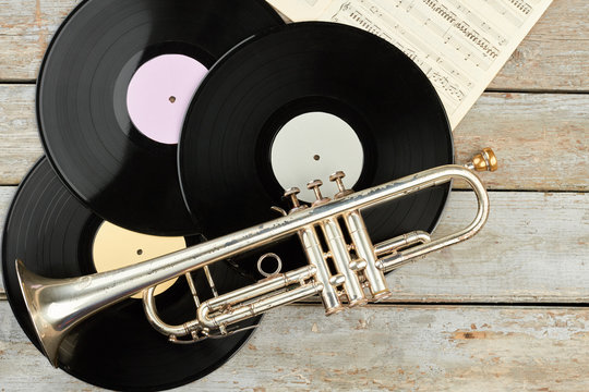 Vinyl records and trumpet on wooden background. Set of musical equipment in vintage style.