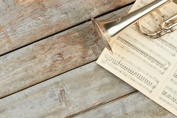 Musical notes, trumpet and copy space. Old trumpet and music pages on old wooden planks. Classical...