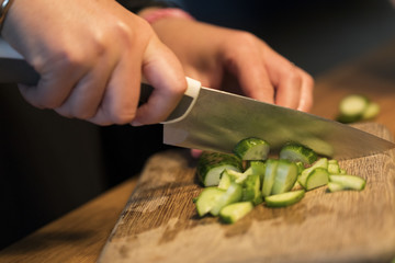 Someone cutting a cucumber on a cutting board