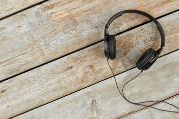 Headphones on old wooden background. Black earphones on rustic wooden boards with copy space. Personal audio device.