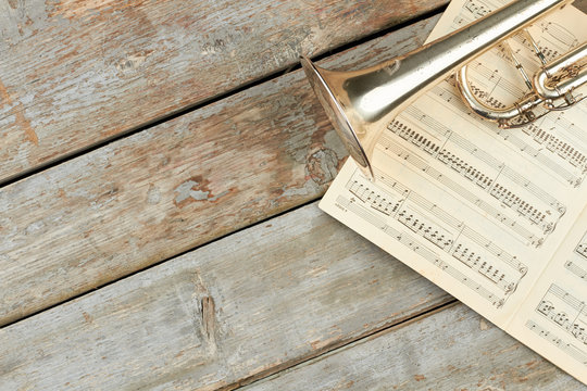 Musical notes, trumpet and copy space. Old trumpet and music pages on old wooden planks. Classical music objects.