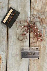 Two audio cassettes on wooden background. Audio tapes on rustic wooden planks, vertical image.
