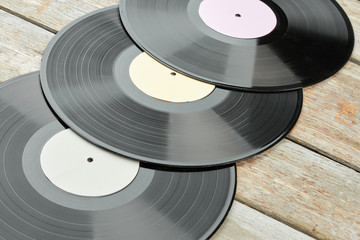 Musical background with vinyl records. Vinyl discs with different labels on wooden background close up. Vintage media equipment.