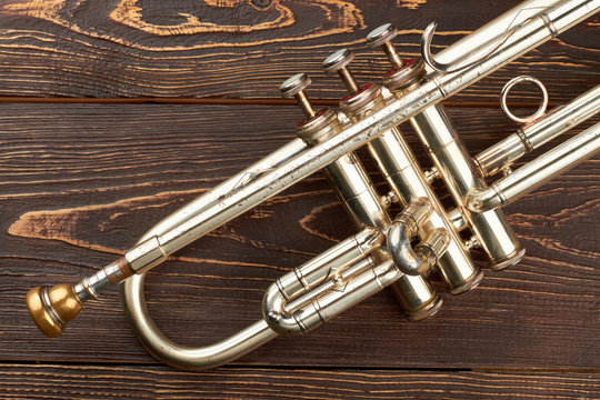 Close up trumpet on brown wooden background. Valve of trumpet instrument. Orchestra music instrument.