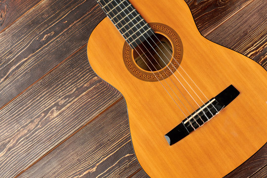 Guitar on brown wooden background. Classical acoustic guitar on wooden surface. Beautiful musical instrument.
