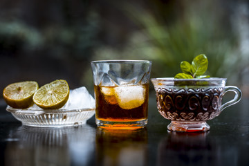 Close up of hangover remedy i.e. lemon juice and black tea in a transparent cup on wooden surface with Scotch or Scotch whiskey or Grain whiskey.