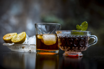 Close up of hangover remedy i.e. lemon juice and black tea in a transparent cup on wooden surface with Scotch or Scotch whiskey or Grain whiskey.
