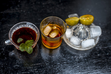 Close up of hangover remedy i.e. lemon juice and black tea in a transparent cup on wooden surface with Scotch or Scotch whiskey or Grain whiskey.