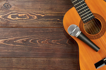Acoustic guitar with microphone on wooden background. Classical guitar with microphone on brown...