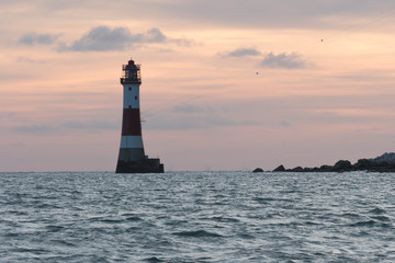 Beachy head lighthouse near Eastbourne in United Kingdom while red sunset behind the lighthouse.