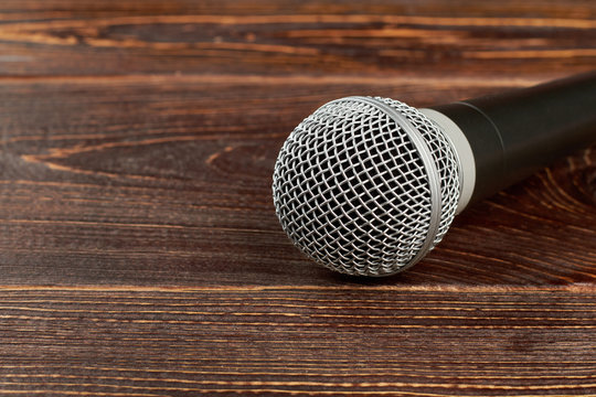 Dynamic microphone on wooden background. Gray microphone on textured wooden table with copy space.