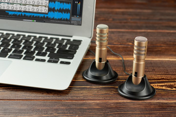 Laptop and stereo record microphone. Mini stereo condenser microphones and laptop computer on brown...