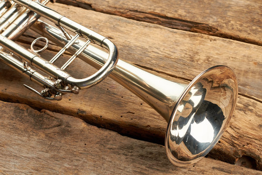 Close up trumpet on rustic wooden floor. Classical trumpet with mirror reflection. Vintage wind instrument.