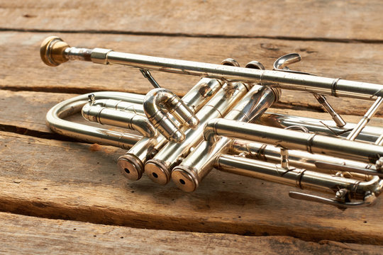 Herald trumpet on old wooden background. Valve of vintage trumpet instrument. Orchestra music instrument on rustic floor.