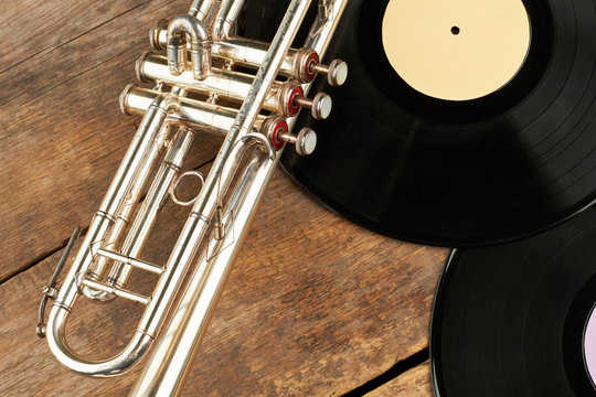 Old trumpet and vinyl records. Musical background with gramophone records and trumpet. Vintage musical equipment.