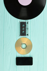 Old and modern technology on wooden background. Vinyl record, cassette tape, CD disc and...